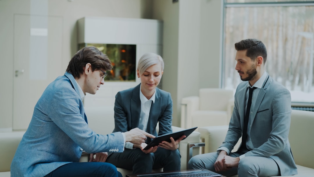 Panning shot of businessman discussing financial reports with female and male business partners sitting on sofa in modern office hall with indoors